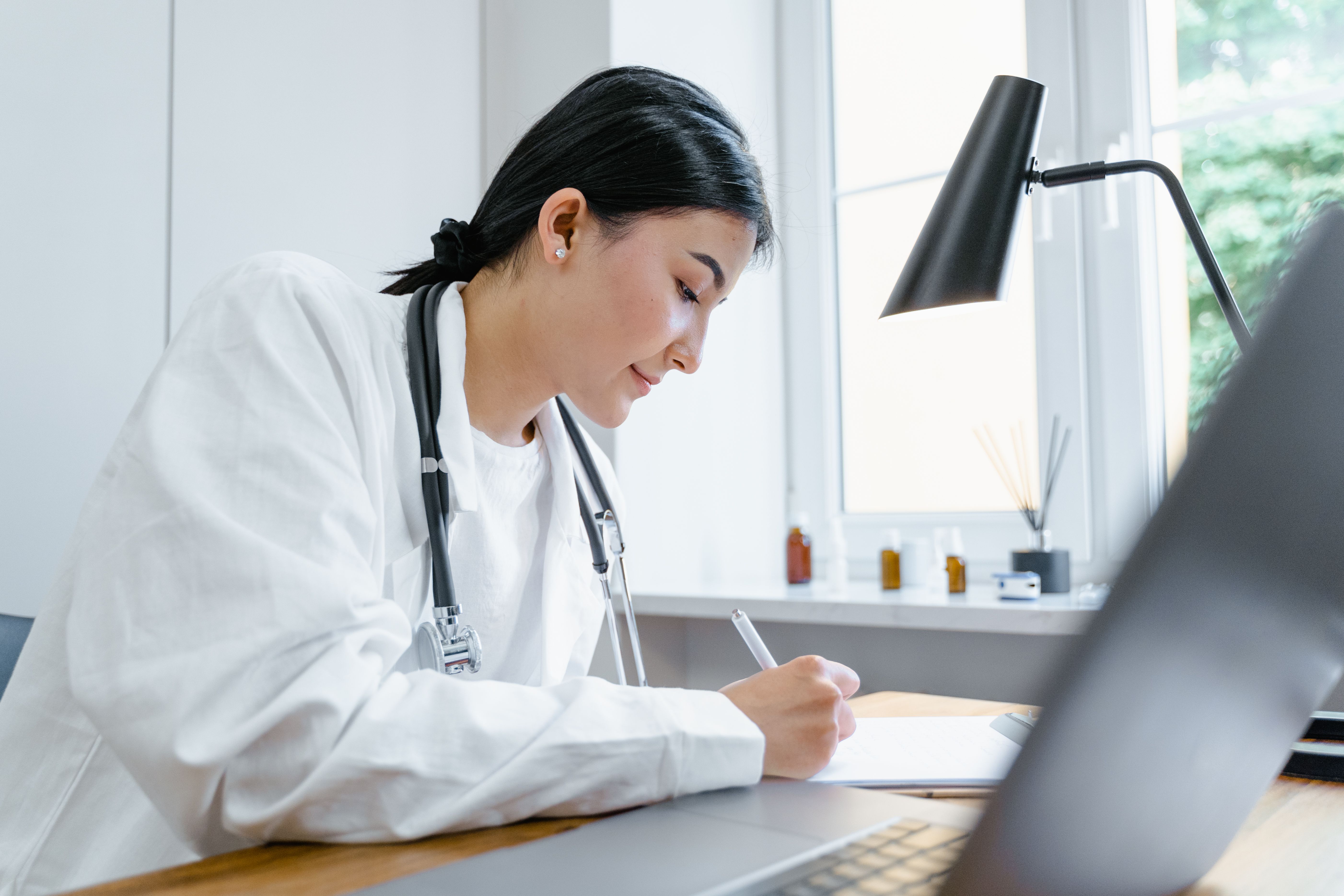 Clinician at a desk reviewing AI-generated clinical notes comparing AI scribe vs manual documentation